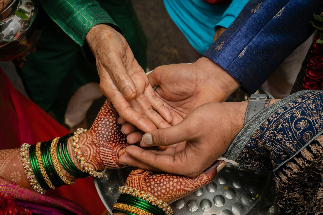 Group of coworkers joining hands over a table in an office